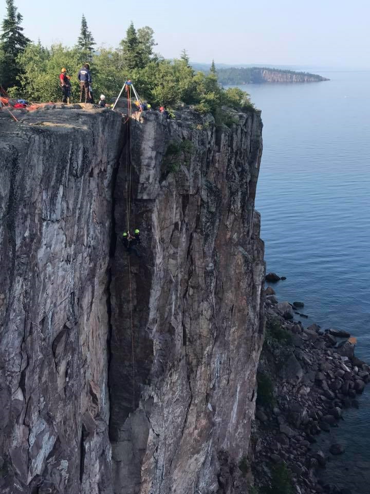 rock climbers at the top of a steep cliff