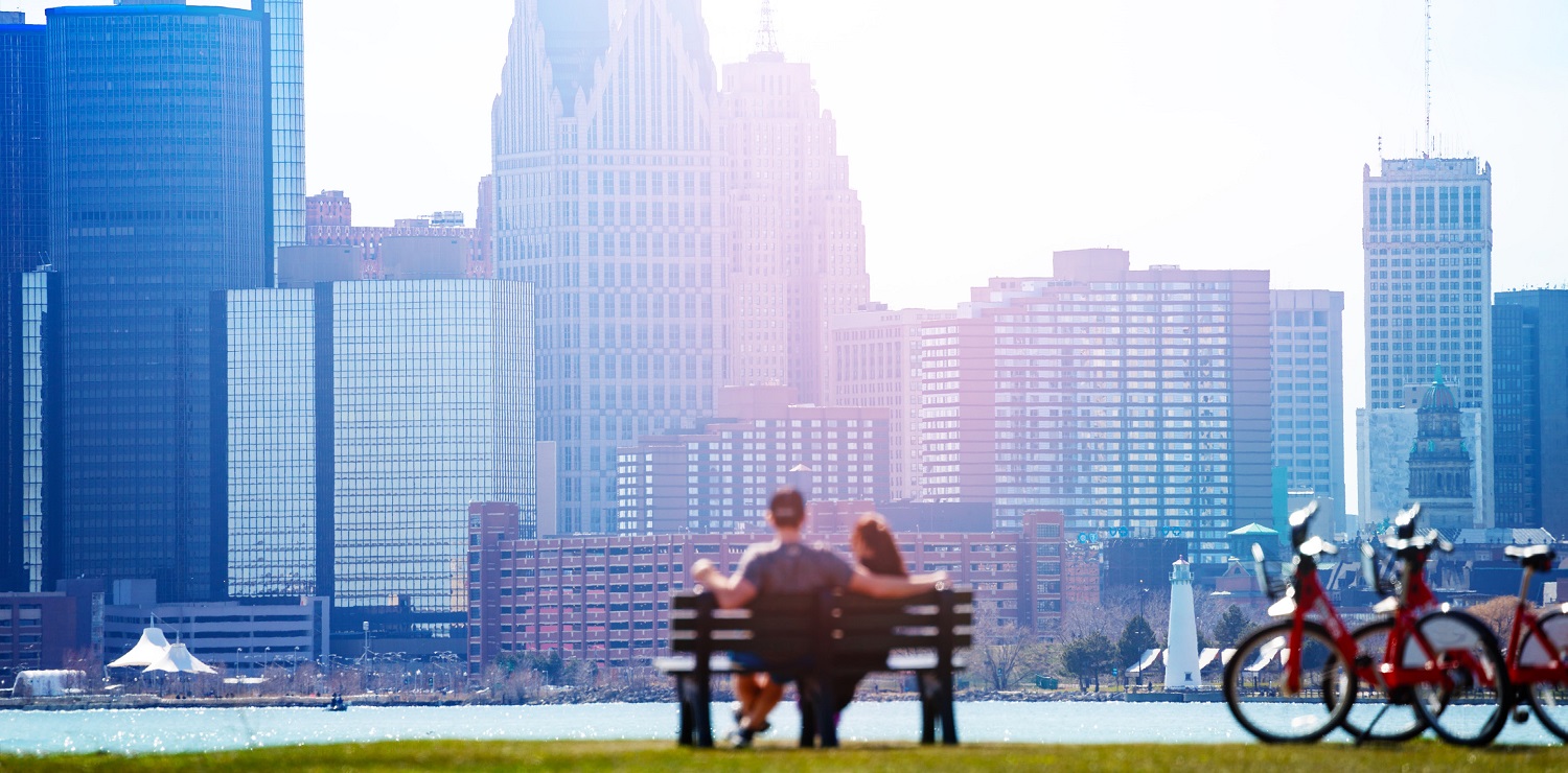 People at a bench park looking at a city's downtown