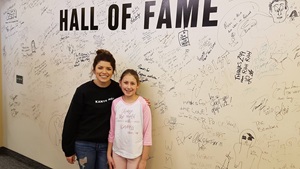 Girl with radio DJ in front of wall of signatures