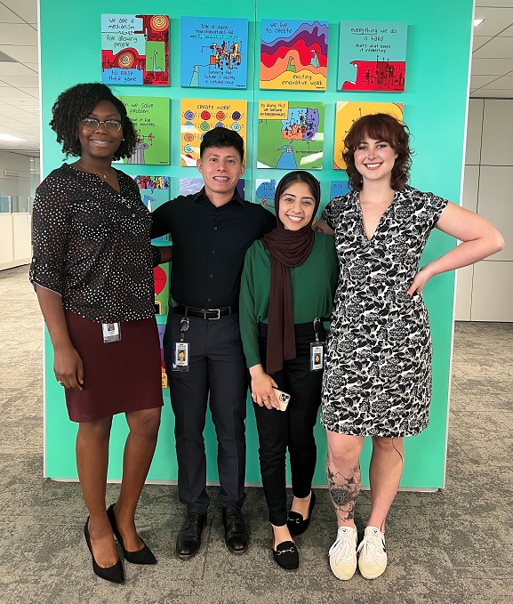 Four young people in front of a mural