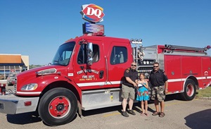 Girl with two firefighters in front of fire truck