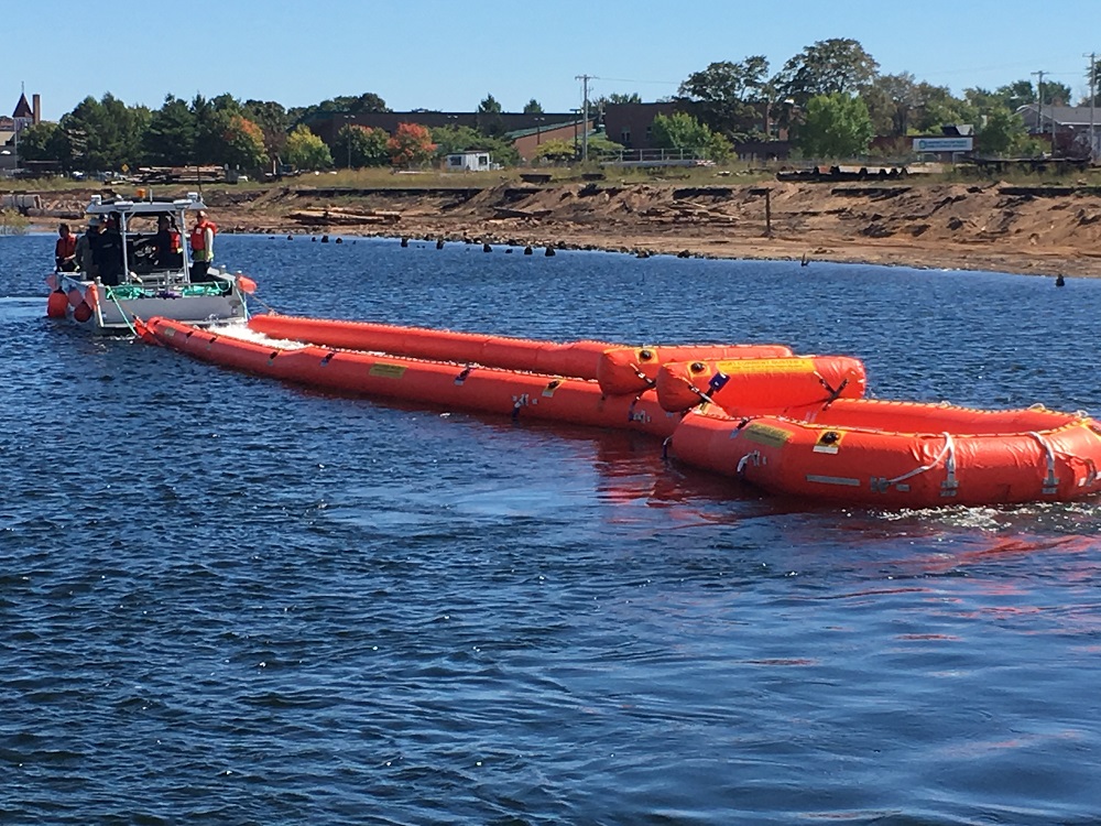 Boat and containment boom on water
