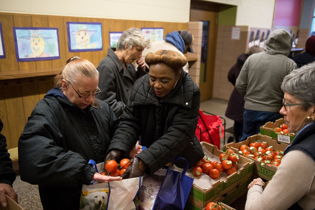 food bank volunteer helping client choose tomatoes