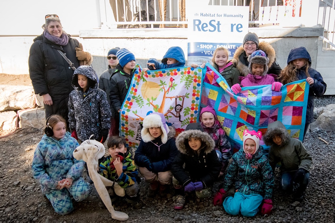 Children holding up quilts