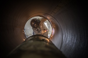 worker seen from inside a pipe
