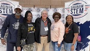 Five adults in front of a banner stand