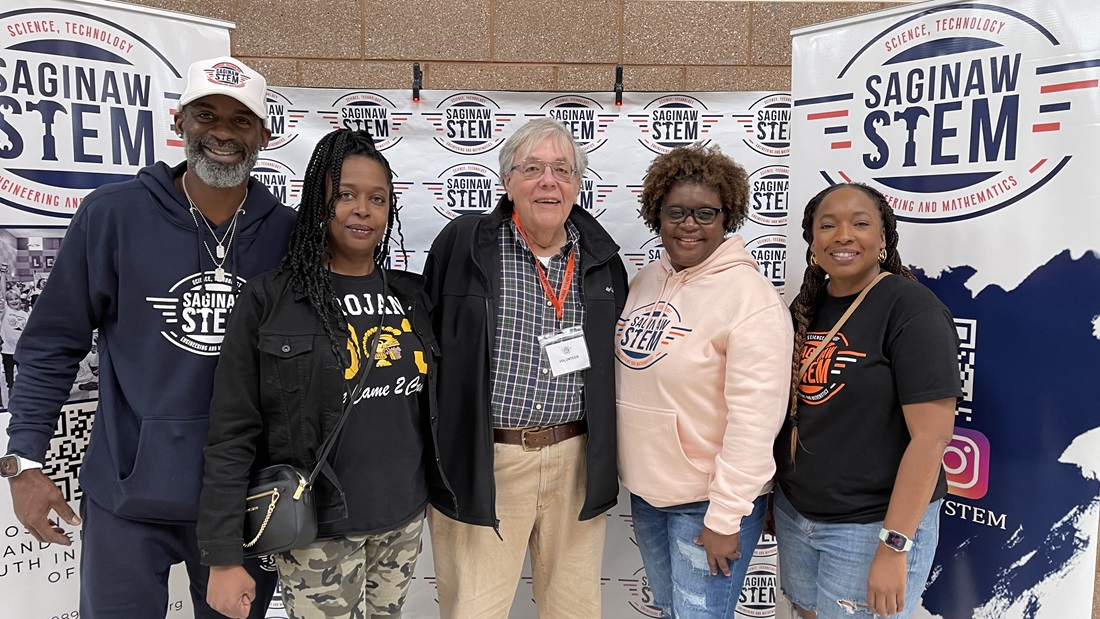 Five adults in front of a banner stand