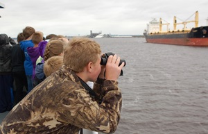 Student looking across river with binoculars