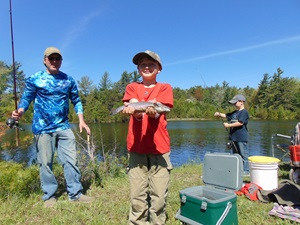 Boy holds a fish he caught in a lake