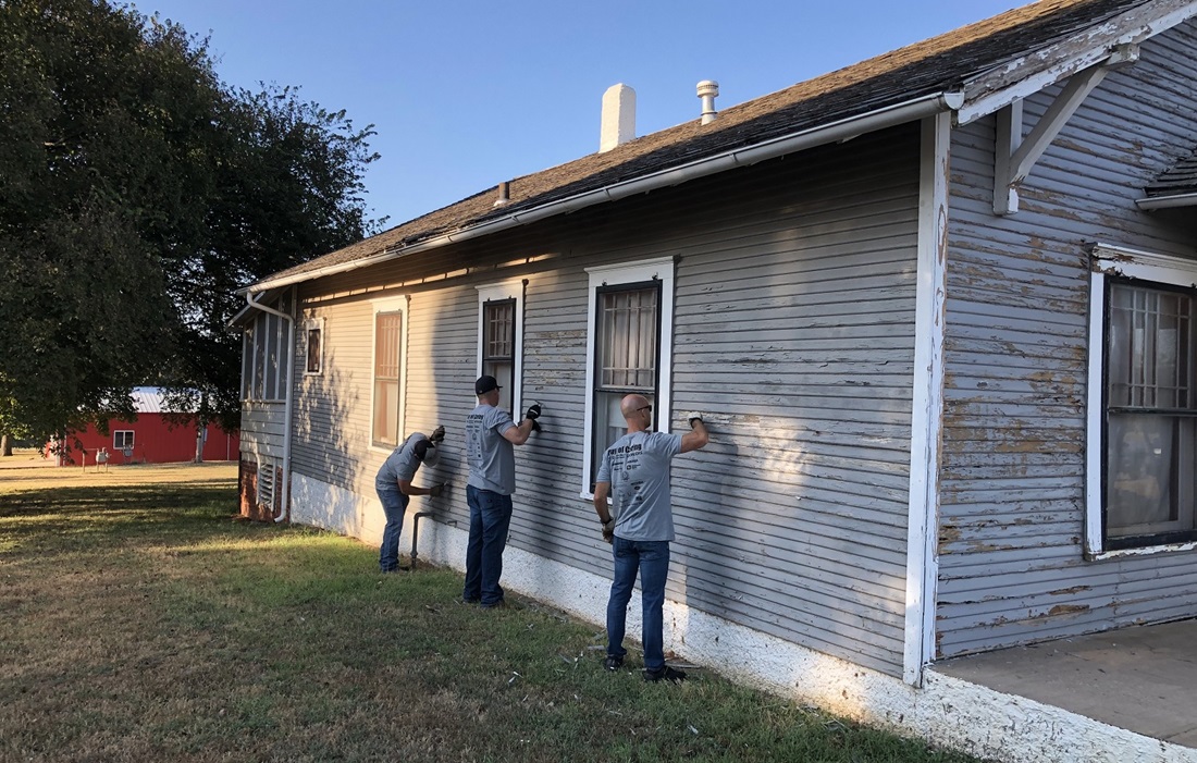 People sanding and painting a house