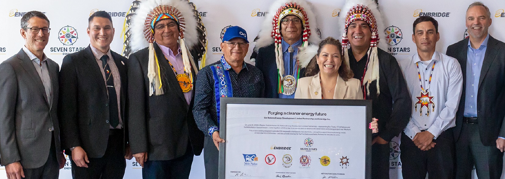 Large group of people, including First Nations Chiefs, holding up framed document
