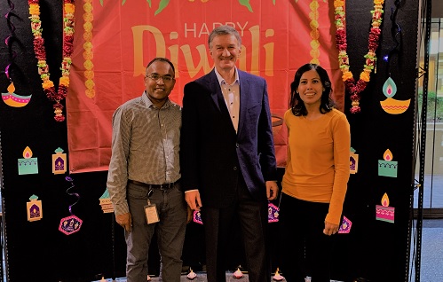 People in front of a cloth backdrop reading Happy Diwali