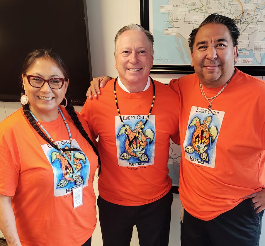 Three people in orange shirts