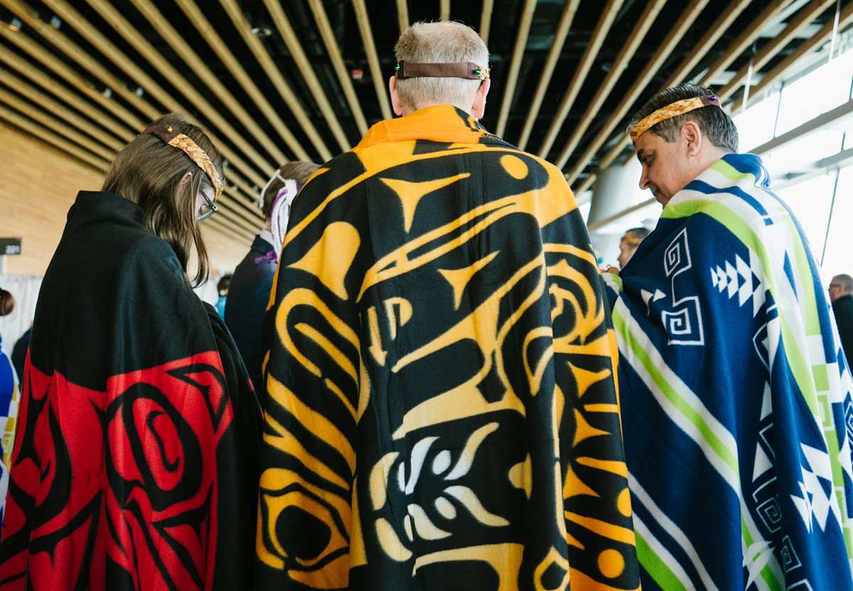 People dressed in robes with Haida artwork