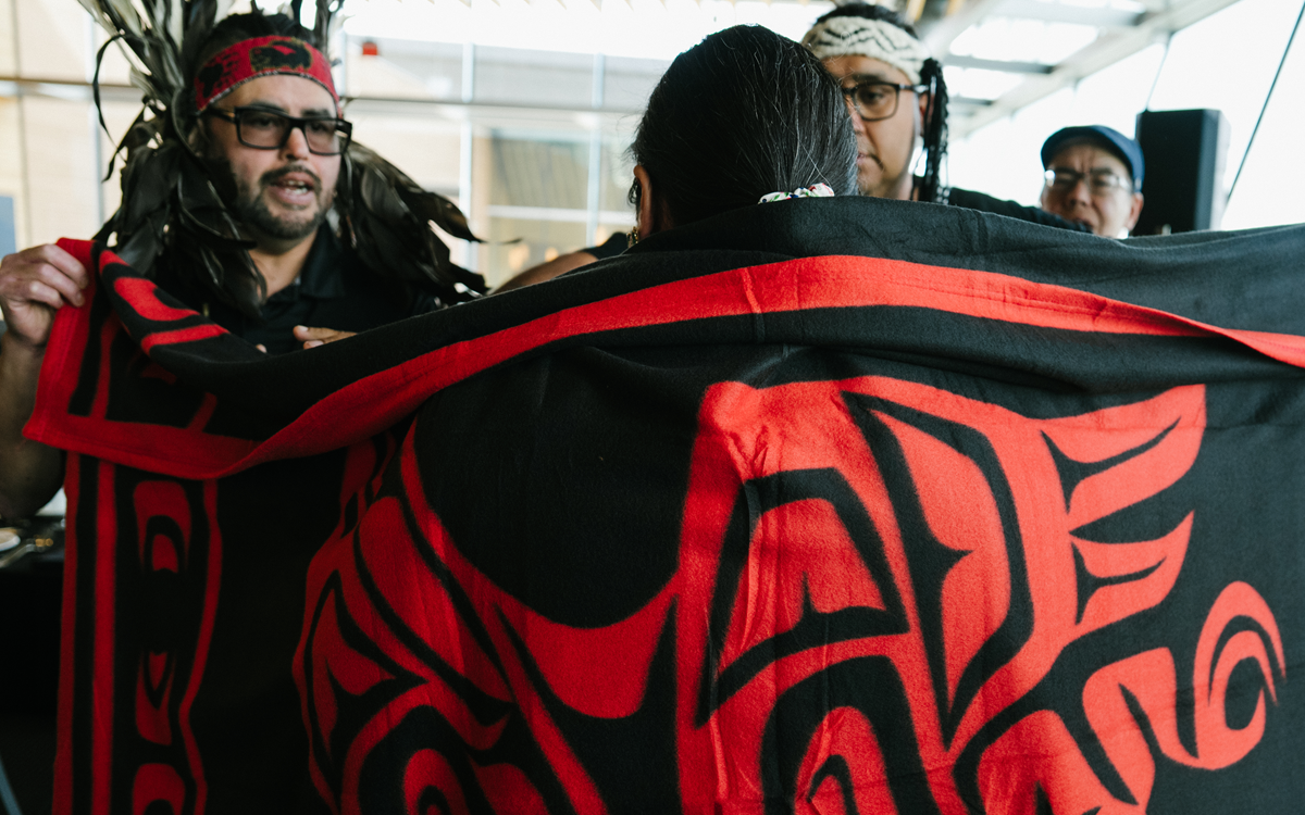 Woman being wrapped in a robe with Haida art