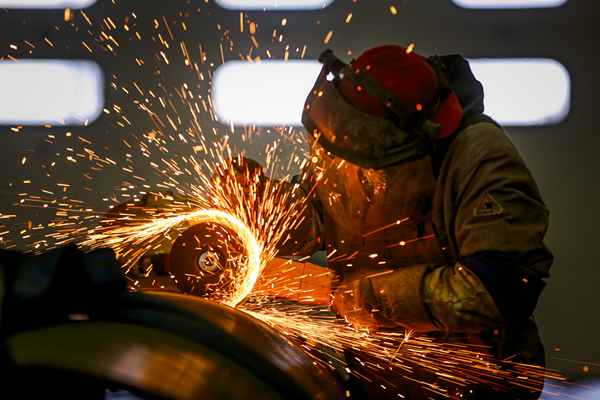 Welder grinding pipe and making sparks