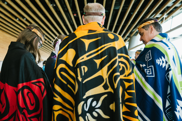 People in robes with Haida artwork