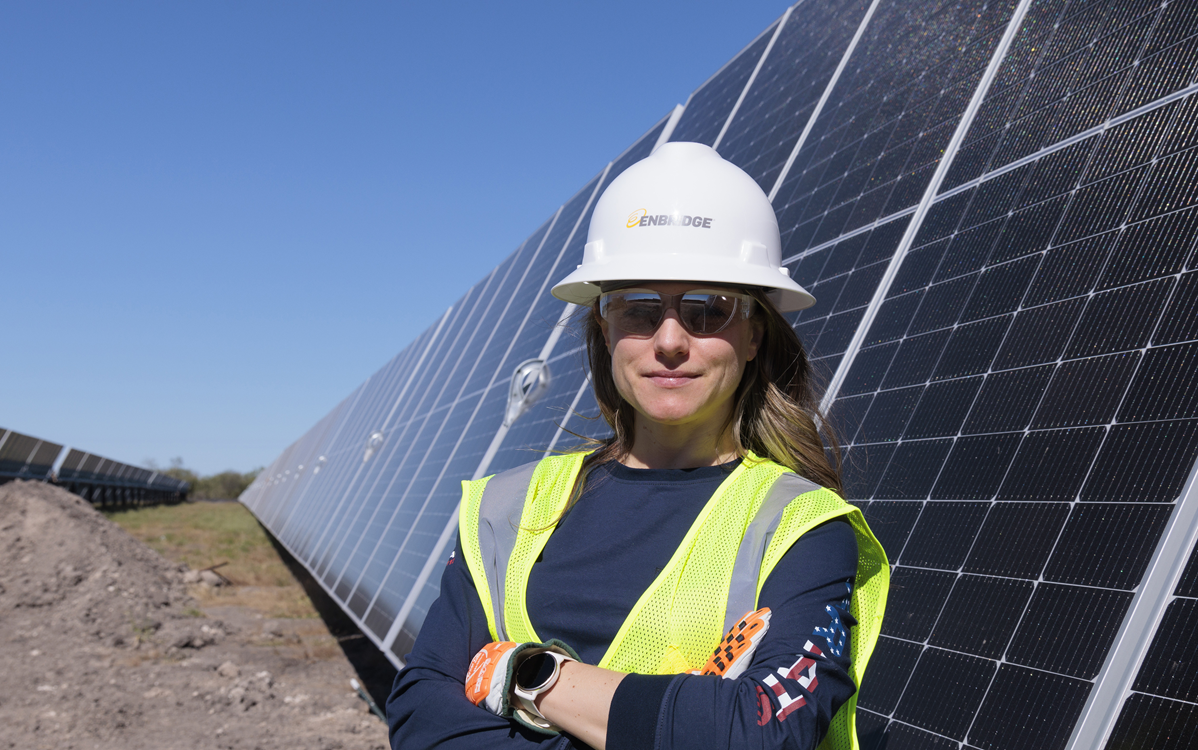 Woman in safety gear in front of solar panels