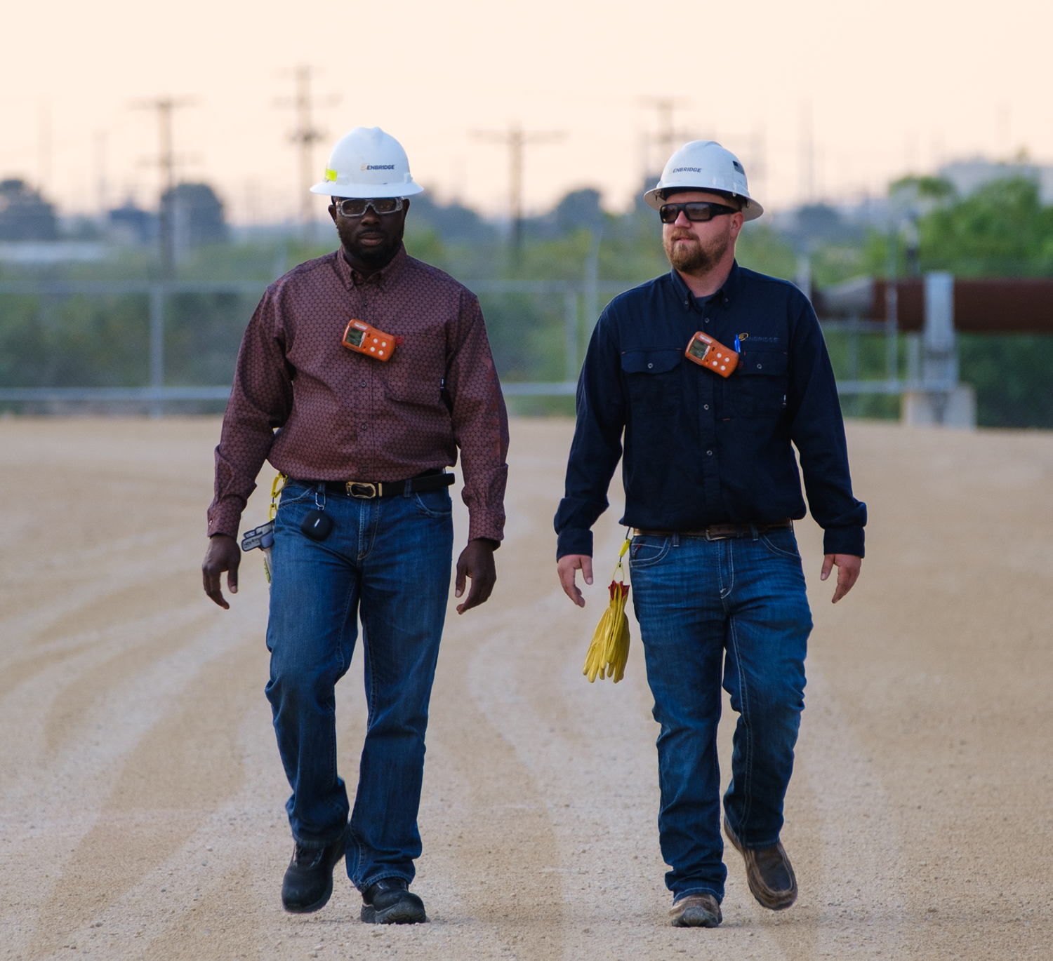 Two workers in hardhats walking at dusk