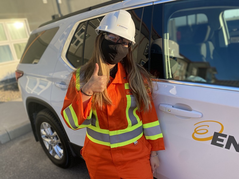 Young woman giving thumbs up beside a vehicle