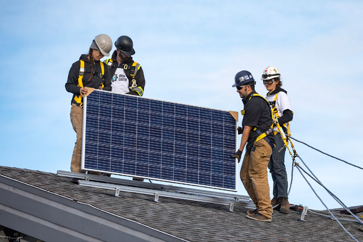 Workers installing a solar panel on residence