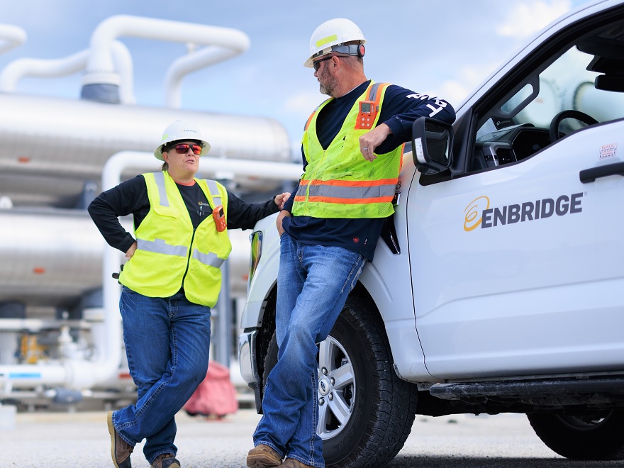 Two employees in safety gear beside a truck