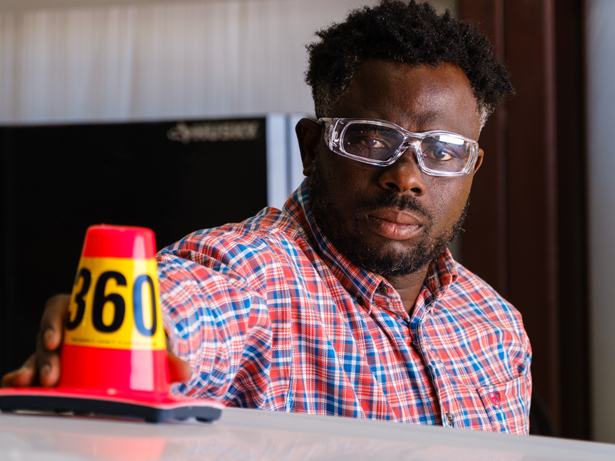 Worker putting a safety cone on hood of his truck