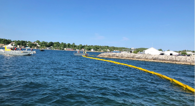 Boats and containment boom on water