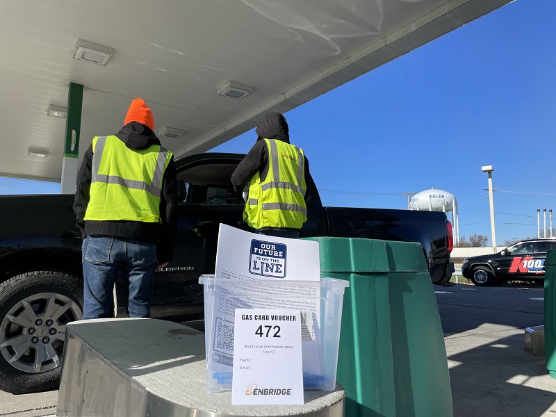 People giving away gas cards at a gas station