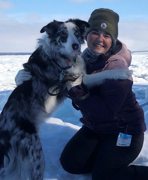 woman in a snowsuit with her dog in winter