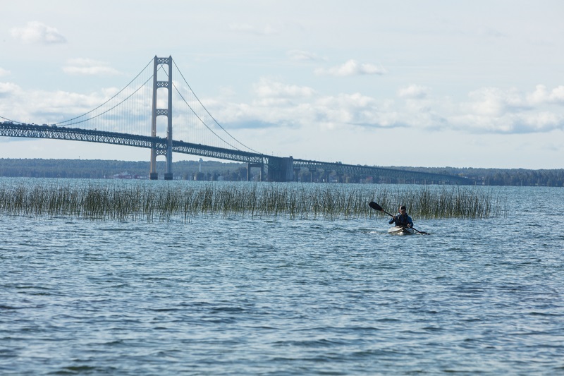 Man kayaking with bridge in the background