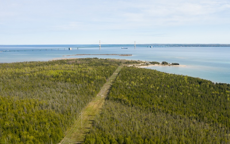Pipeline right of way with body of water and bridge in the background