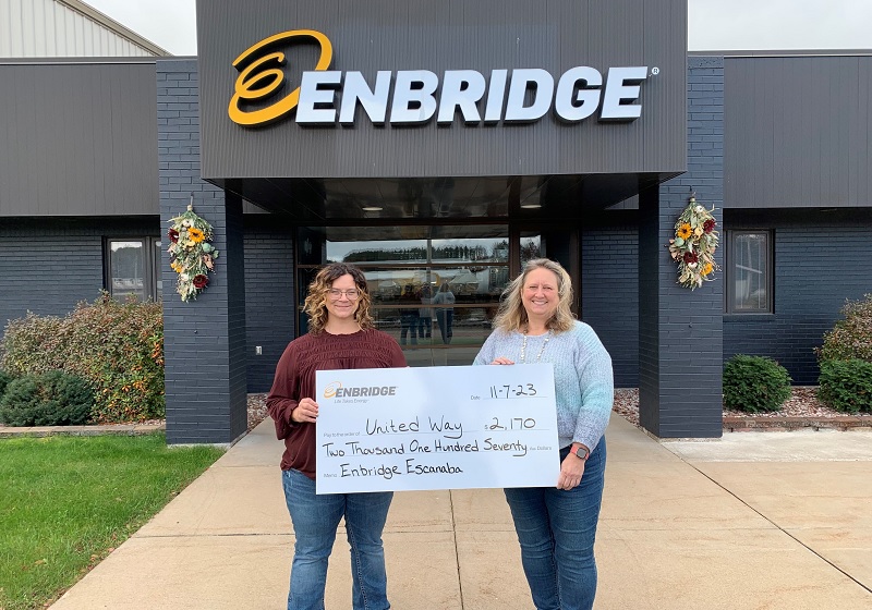 Two people receive a cheque from Enbridge
