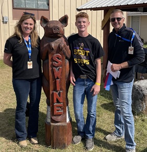 Teenage 4-H winner with a wood statue of a pig