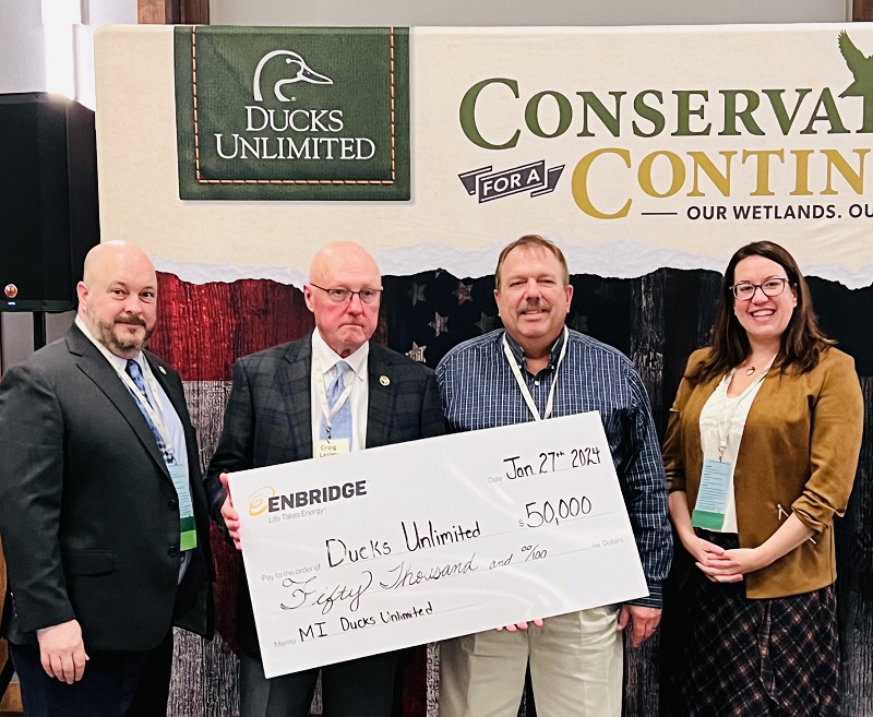 Four people holding a large check