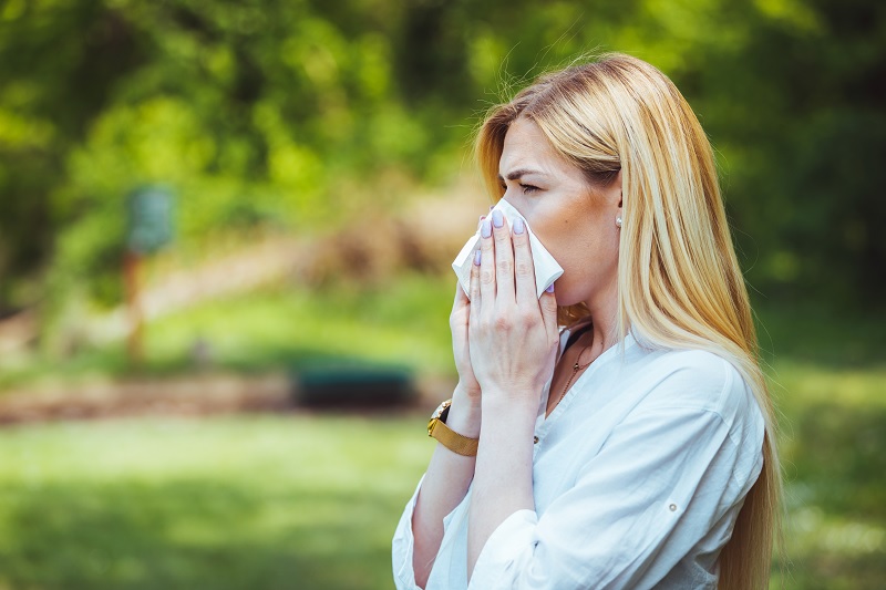 Woman blowing her nose outside