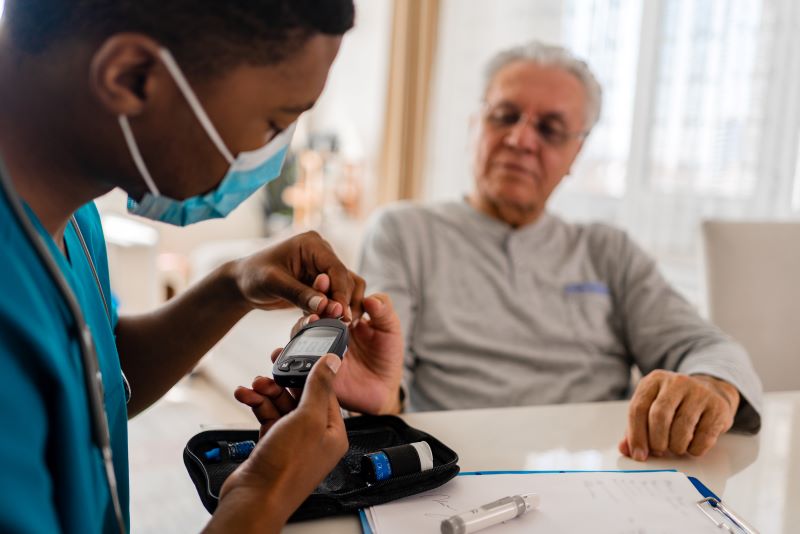 A nurse using a device to measure patient's blood glucose