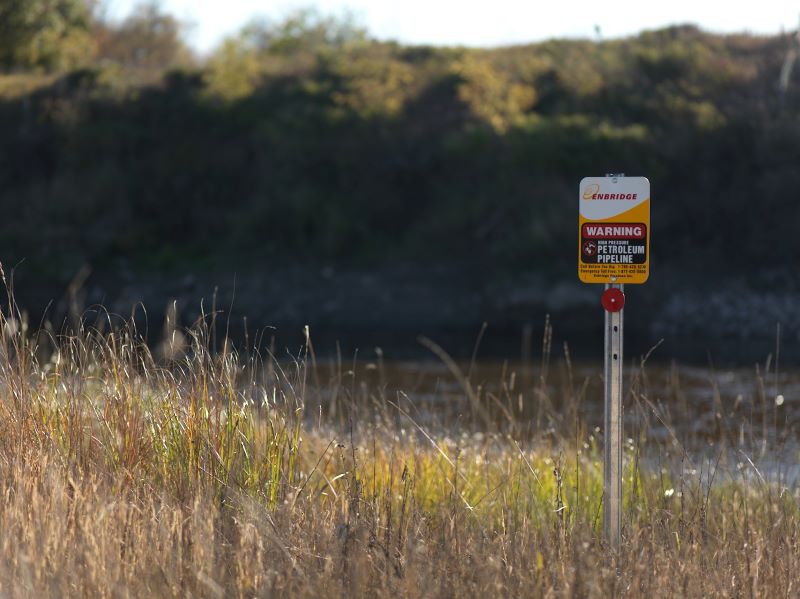 An Enbridge pipeline marker sign outdoors reading 'Warning Petroleum Pipeline'