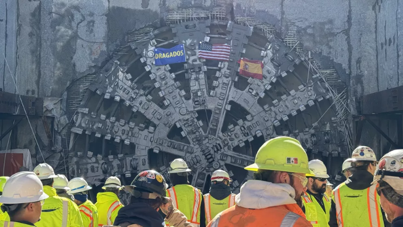 Construction workers in front of a tunnel boring machine.