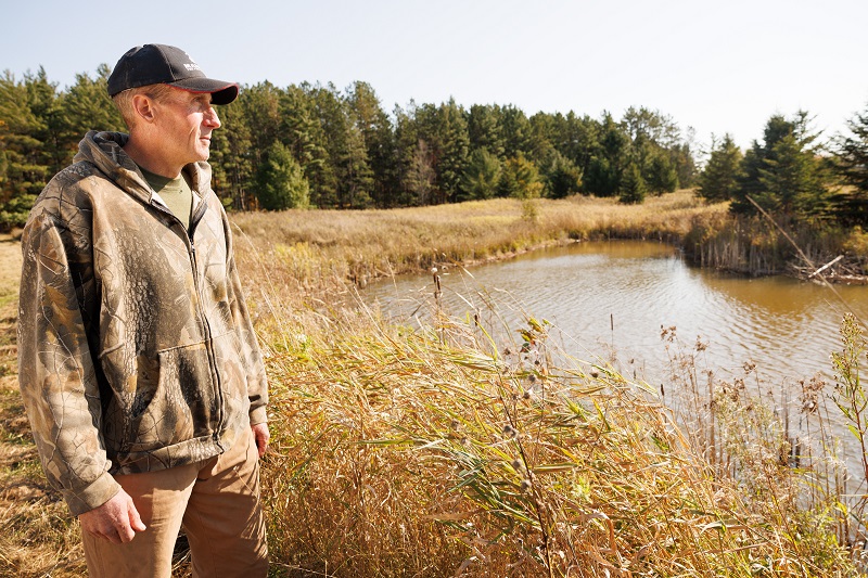 Man standing behind small body of water