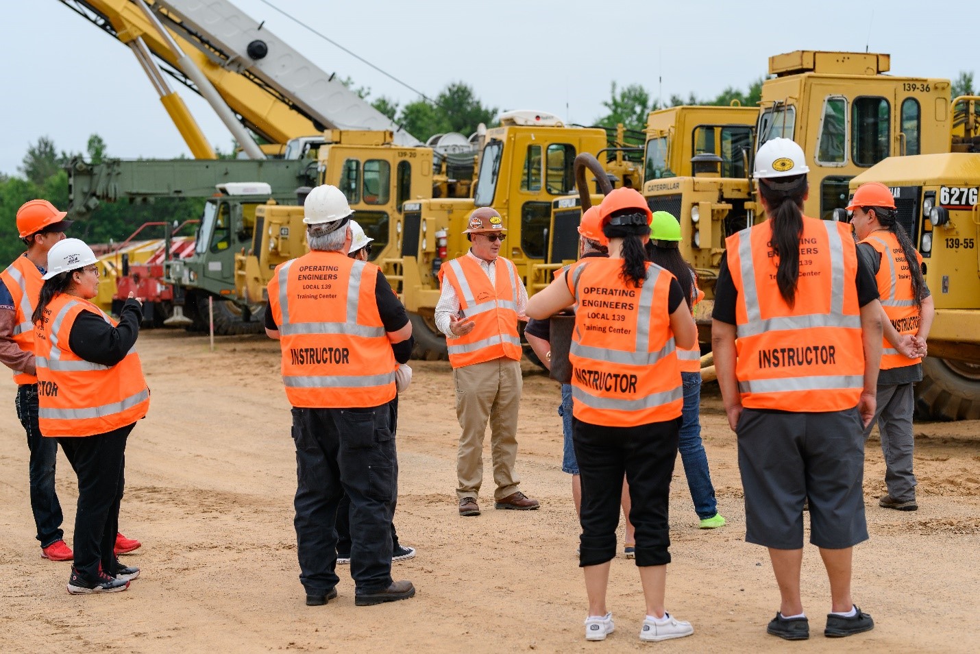 People in safety gear in a heavy equipment yard