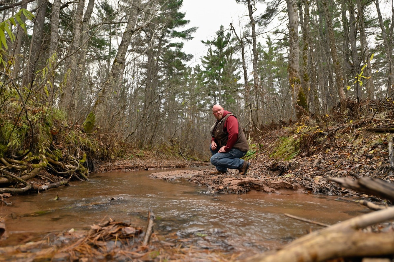 Man kneeling by creek