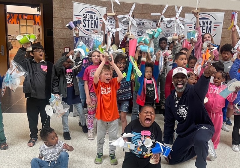 Kids cheering and holding up windmills they made