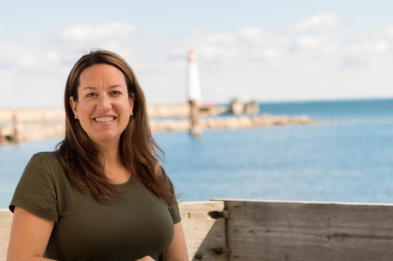 Women smiles at camera with ocean in the back