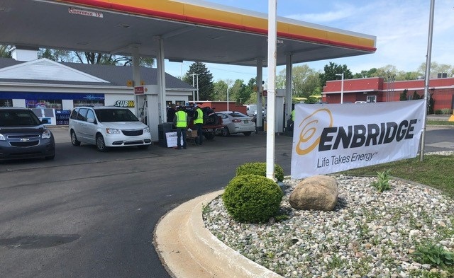 Cars at a gas station with an Enbridge sign at the entrance