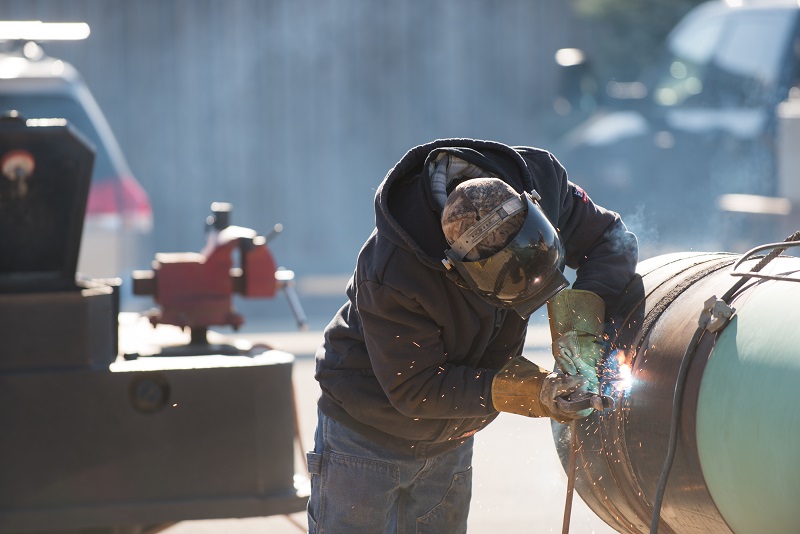 Welder wearing helmet doing stick welding on a pipe