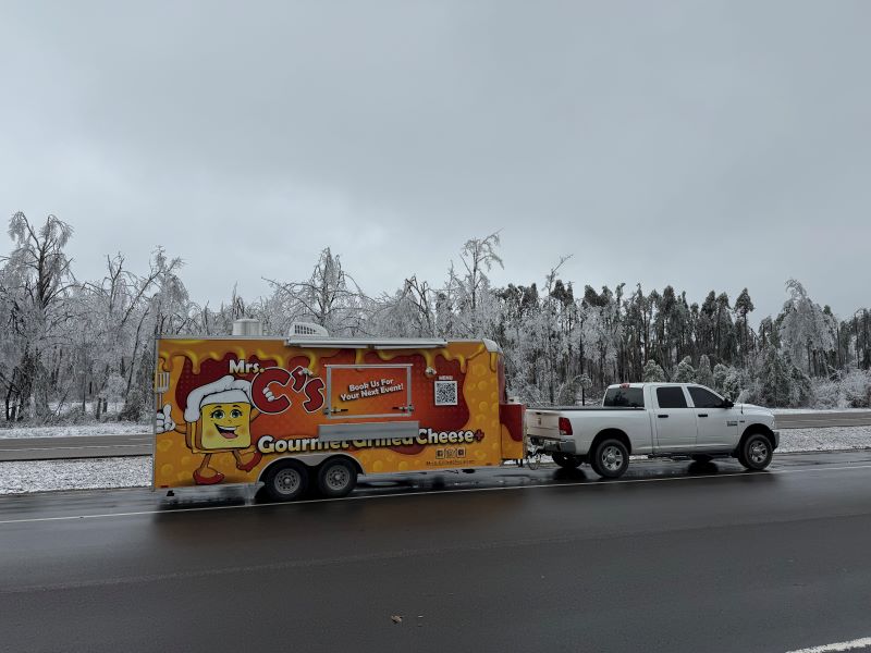 A food truck on a road with icy trees behind