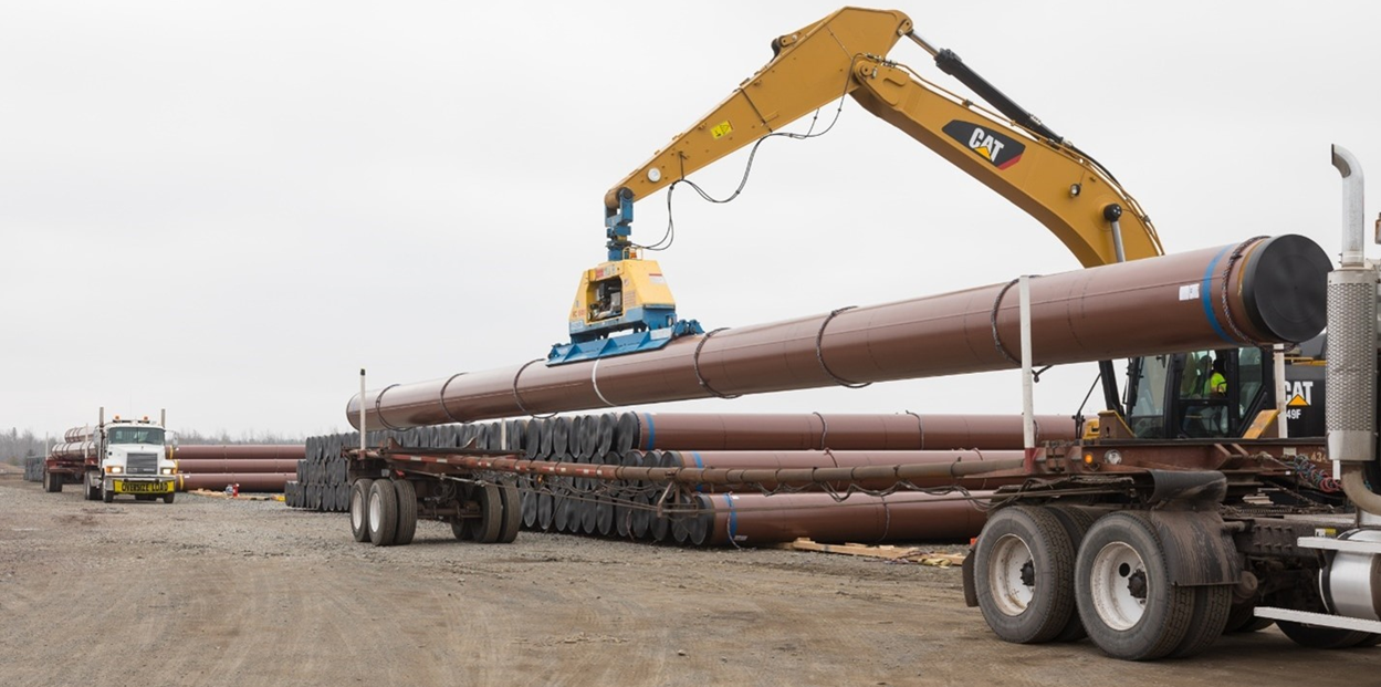 Crane loading pipe segments onto a flatbed truck