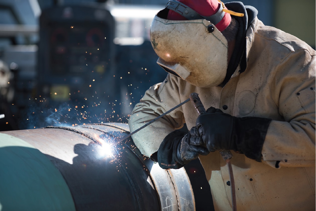 Welder using a rod on a segment of pipe