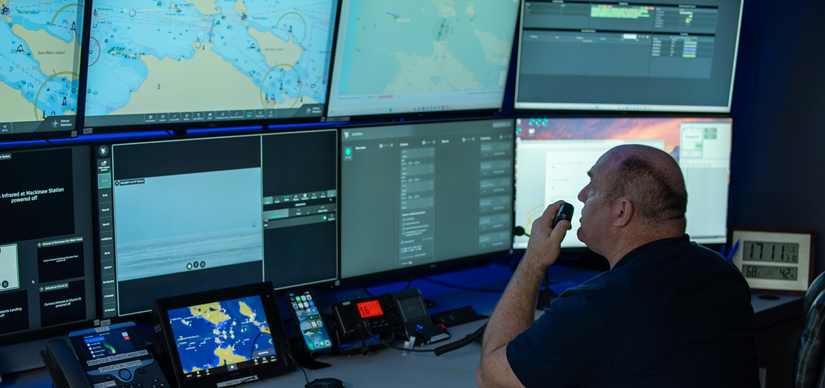 Man monitoring multiple computer screens from a desk